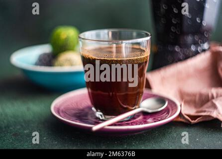 Machine à café geyser près d'un verre de café et pakhlava turque traditionnelle sur une table en béton Banque D'Images
