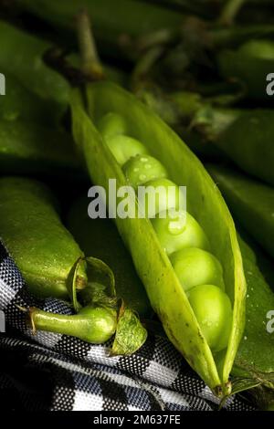 De dessus pile de gousses entières mûres et ouvertes avec des petits pois placés ensemble dans le panier Banque D'Images