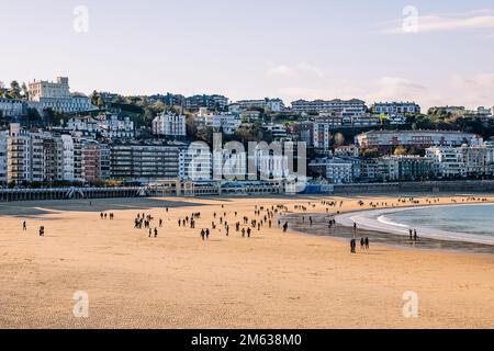 Foule de personnes passant du temps sur la plage de sable de la Concha contre des immeubles d'appartements par jour nuageux à Donostia San Sebastian, Espagne Banque D'Images