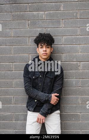 Portrait d'un jeune homme à poil dur ethnique en tenue décontractée debout avec bras croisés regardant l'appareil photo Banque D'Images