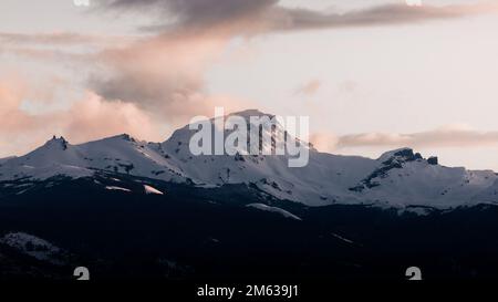 Vue à couper le souffle sur les montagnes immenses et rugueuses couvertes de neige sous un ciel nuageux et sombre au coucher du soleil situé à Cholila Banque D'Images