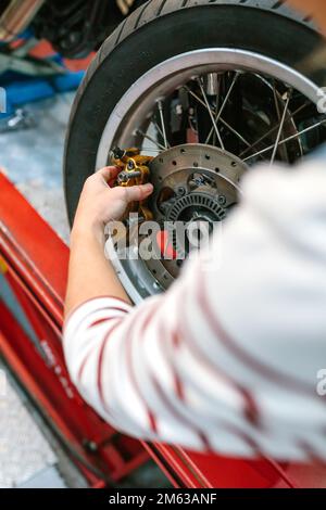 Mécanicien femme changeant le système de freinage à étrier dans la roue de moto Banque D'Images