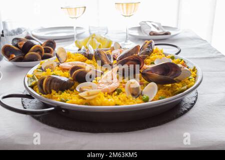 L'espagnol paella aux fruits de mer avec crevettes, palourdes, moules, riz safrané et légumes servi dans un poêlon sur la table de restaurant.Close up Banque D'Images