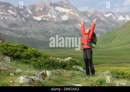 Randonneur excité dans les bras rouges levant célébrant des vacances dans la nature avec un beau paysage en arrière-plan Banque D'Images