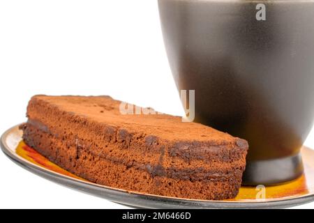 Un morceau de gâteau à la truffe sur une soucoupe en céramique avec une tasse noire, macro, isolée sur fond blanc. Banque D'Images