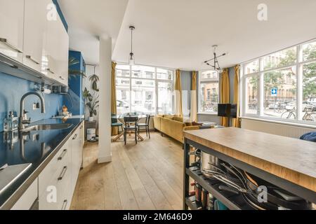 une cuisine et salle à manger dans une maison avec murs bleus, parquet et appareils électroménagers blancs sur le mur Banque D'Images