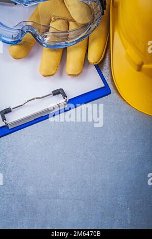 Lunettes de sécurité gants bloc-notes casque de construction sur fond métallique. Banque D'Images