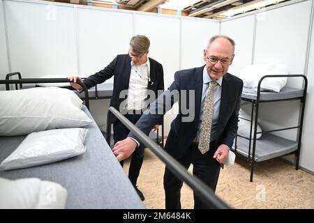 Friedrichshafen, Allemagne. 02nd janvier 2023. Lothar Wölfle (r, CDU), administrateur de district du district de Constance, et chef des affaires sociales, Ignaz Wetzel, regardent une aire de vie dans un refuge d'urgence après avoir expliqué le concept d'accueil du district. La salle de sport de l'école professionnelle de Friedrichshafen a été transformée en hébergement d'urgence pour les réfugiés. Jusqu'à 240 personnes peuvent être hébergées. Credit: Felix Kästle/dpa/Alay Live News Banque D'Images