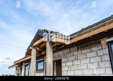 Carreaux de céramique posés en paquets sur le toit sur des lattes, piliers en béton visibles à l'entrée de la maison. Banque D'Images