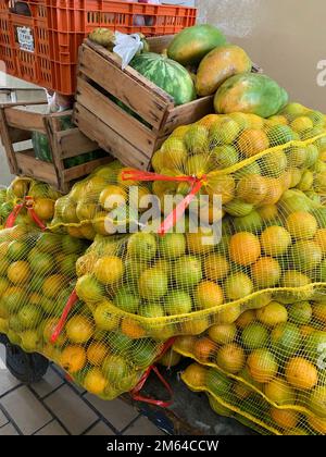 Sacs en maille jaune d'oranges pillés sur le chariot avec une caisse de papaye Banque D'Images