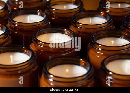 Un ensemble de bougies de cire de noix de coco et de soja différents dans des pots de verre brun. Bougie parfumée faite à la main. Bougies de soja dans un pot d'ambre. Aromathérapie et détente Banque D'Images