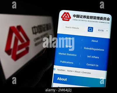 Personne tenant un téléphone portable avec le site Web de la Commission chinoise de réglementation des valeurs mobilières (CSRC) à l'écran avec le logo. Concentrez-vous sur le centre de l'écran du téléphone. Banque D'Images