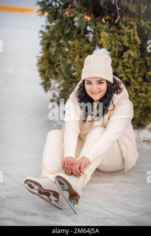 Belle fille s'amuser et mettre sur des patins à glace sur fond d'arbre de noël, Prague, République Tchèque Banque D'Images