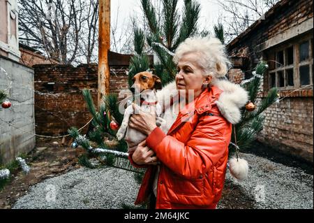 ORIKHIV, UKRAINE - 30 DÉCEMBRE 2022 - Une femme âgée tient un chien près d'un arbre de Noël endommagé dans la ville d'Orikhiv qui est bombardé par la Russie Banque D'Images