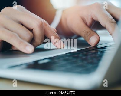 Gros plan de la personne en voyage d'affaires en costume toucher sur le pavé tactile tout en tapant sur le clavier de l'ordinateur portable. Travail sur ordinateur portable, technologie d'entreprise con Banque D'Images