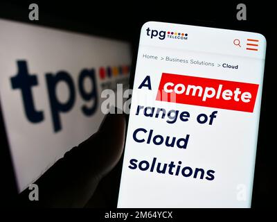 Personne tenant un téléphone portable avec la page Web de la société australienne TPG Telecom Limited à l'écran devant le logo. Concentrez-vous sur le centre de l'écran du téléphone. Banque D'Images