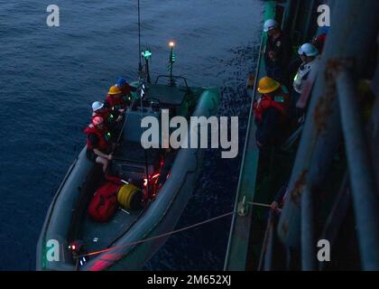 220402-N-CM110-2257 OCÉAN PACIFIQUE (2 avril 2022) – des marins à bord d'un navire d'assaut amphibie USS Tripoli (LHA 7) lèvent un bateau gonflable à coque rigide (RHIB) au cours d'une évolution d'entraînement, 2 avril. Tripoli mène actuellement des opérations de routine dans la flotte américaine 3rd. Banque D'Images