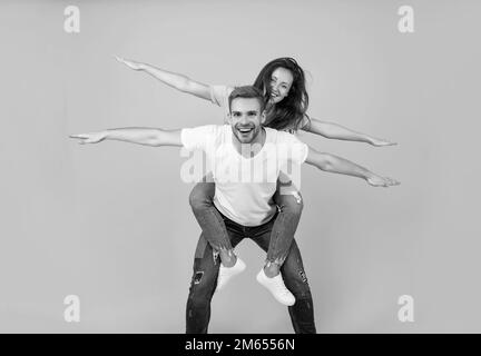 Écartez vos ailes et envolez-vous.Une femme heureuse aime faire du pigeyback sur un gars.Couple amoureux de s'amuser.Profitez de chaque instant. Banque D'Images