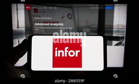 Personne tenant un smartphone avec le logo de la société américaine de logiciels d'entreprise Infor à l'écran devant le site Web. Mise au point sur l'affichage du téléphone. Banque D'Images