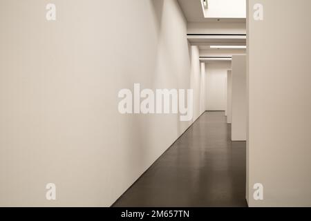 Intérieur vue en perspective décroissante du couloir entre le mur blanc et les cloisons à l'intérieur de la galerie. Banque D'Images