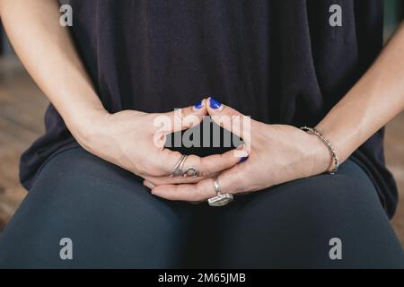 Photo rapprochée des mains d'une femelle yogi méditant dans une posture agenouillée (vajrasana) pendant son entraînement de yoga de flux de vinyasa seul portant des vêtements de sport Banque D'Images
