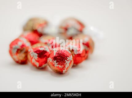 gros plan de plusieurs bonbons de noël en forme de boule de chocolat enveloppés de papier d'aluminium rouge Banque D'Images