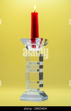 une bougie rouge avec une flamme orange jaune en verre clair sculptée porte-bougie Banque D'Images