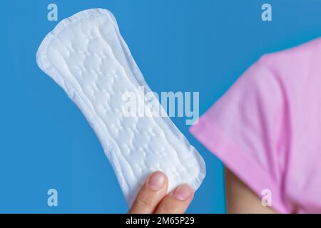 Fille tenant dans un tampon d'hygiène des mains sur fond bleu. Banque D'Images