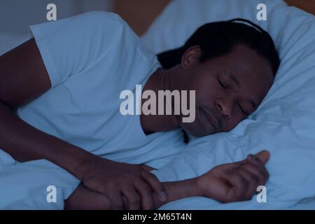 Portrait du jeune Africain américain endormi au lit pendant la nuit Banque D'Images