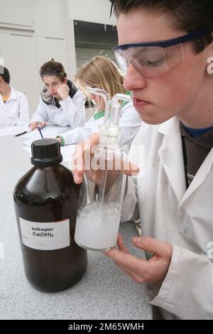 Pays-Bas, un étudiant pendant une leçon de chimie souffle dans l'eau de chaux pour montrer le dioxyde de carbone dans l'air qu'il respire. Banque D'Images