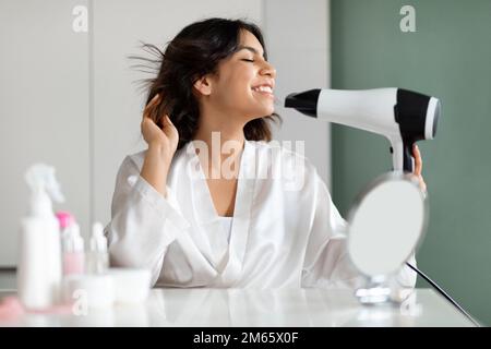 Tricherie moyenne-orientale femme s'amusant tout en coiffant les cheveux Banque D'Images