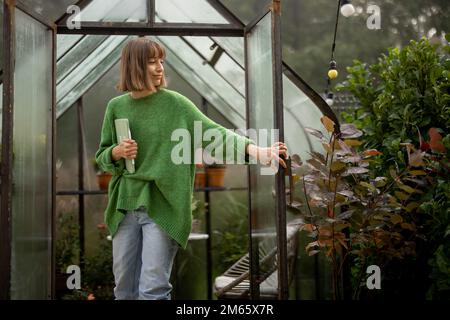 Femme près de la serre dans le jardin Banque D'Images