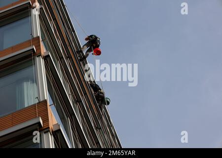 Des nettoyants pour vitres sont suspendus sur une façade à Hambourg et nettoient les fenêtres Banque D'Images