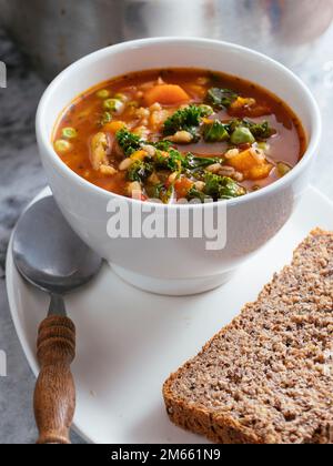 La maison a fait la soupe italienne de minestrone d'hiver avec courge d'hiver, carottes, kale, haricots verts, pois, tomates et orge. Banque D'Images