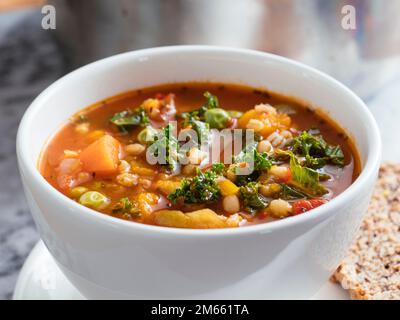 La maison a fait la soupe italienne de minestrone d'hiver avec courge d'hiver, carottes, kale, haricots verts, pois, tomates et orge. Banque D'Images