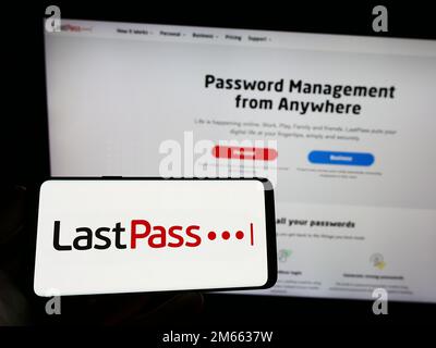 Personne détenant un smartphone avec le logo de la société de gestion de mots de passe LastPass US LP sur l'écran devant le site Web. Mise au point sur l'affichage du téléphone. Banque D'Images