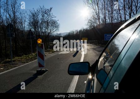 Photo dynamique des travaux de route vus de l'intérieur d'une fenêtre de voiture. L'image montre des panneaux d'avertissement et des signaux avertissant les conducteurs de la construction Banque D'Images