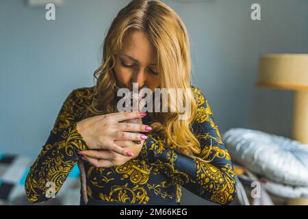 Une femme blonde tenant et embrassant un chat Devon rex. Concept PET. Portrait. . Photo de haute qualité Banque D'Images