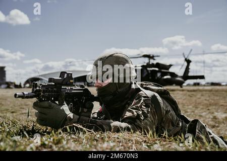 Un soldat des forces armées polonaises scanne son secteur en tant qu'américain L'hélicoptère d'évacuation médicale UH-60 Blackhawk de l'armée du 1-214th Bataillon de l'aviation générale, 12th Brigade de l'aviation de combat, charge du personnel en arrière-plan, lors d'un exercice conjoint mené par les forces armées polonaises dans la zone d'atterrissage près de l'arène G2A, Pologne, 8 avril 2022. Cet exercice, ainsi que d'autres, renforce notre interopérabilité avec nos alliés et partenaires de l'OTAN et renforce les relations régionales que nous avons développées. 12 CAB est la seule brigade d'aviation durable présente dans toute l'Europe qui nous permet du faire Banque D'Images