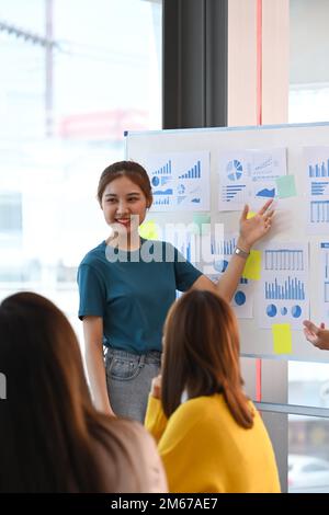 Jeune femme confiante partageant des idées stratégie d'affaires, expliquant de nouvelles stratégies sur tableau blanc à ses collègues Banque D'Images