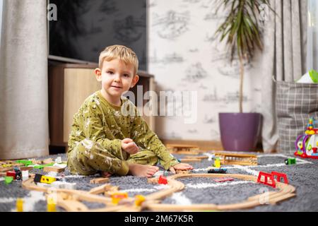 Bébé jouant avec le chemin de fer, les trains et les voitures sur le sol Banque D'Images