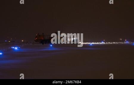 Un membre de l'escadron du génie civil 319th utilise une chasse-neige pour dégager la ligne de vol pendant un blizzard à la base aérienne de Grand Forks, N.D., 12 avril 2022. Par mauvais temps, l'équipe travaille de jour comme de nuit pour éliminer la neige et rétablir la fonctionnalité du terrain d'aviation. Banque D'Images