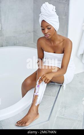 Proche pour plus de confort. Photo en grand angle d'une jeune femme se rasant les jambes près d'une baignoire. Banque D'Images