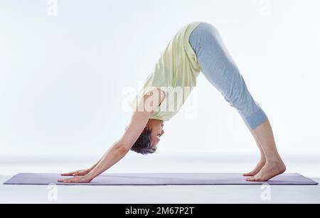 Étirant son dos. Prise de vue en longueur d'une femme attirante qui s'étire avant le yoga. Banque D'Images