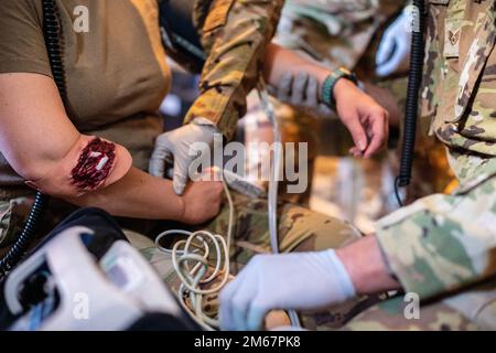 ÉTATS-UNIS Des aviateurs de l'escadron d'évacuation aéromédical 60th effectuent des procédures médicales sur une plaie simulée pendant l'entraînement à bord d'un C-130J Super Hercules affecté à l'escadron de transport aérien 317th, base aérienne Dyess, Texas, au cours d'un entraînement à la base aérienne de Travis, Californie, 13 avril 2022. La mission de l'AE est d'offrir des soins de confiance dans les airs aux membres du service, aux personnes à charge, aux anciens combattants et aux alliés. Ces formations de routine améliorent la capacité des aviateurs à réagir à des situations réelles en un instant. Banque D'Images