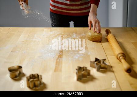 Une femme méconnue saupoudrer la farine sur une table pour faire rouler la pâte Banque D'Images