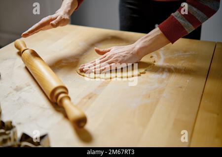 Une femme méconnaissable roule de la pâte pour faire des biscuits au gingembre Banque D'Images