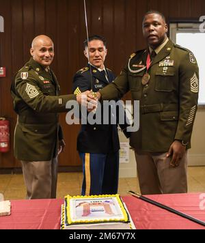 De gauche à droite, le Sgt. Jorge Oquendo, commandant de la brigade médicale 30th, le Sgt. Eric Bornman, 67th DSRF et le Sgt. Gary Petty, commandant de l'hôpital 519th, préparent la coupe du gâteau lors de la cérémonie d'initiation des NCO, à 14 avril 2022, à Sembach, en Allemagne Banque D'Images