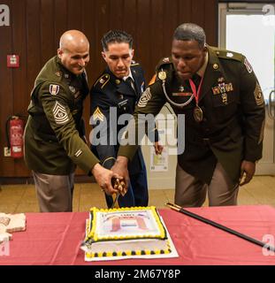 De gauche à droite, le Sgt. Jorge Oquendo, commandant de la brigade médicale 30th, le Sgt. Eric Bornman, 67th DSRF et le Sgt. Gary Petty, commandant de l'hôpital 519th, coupant le gâteau lors de la cérémonie d'initiation de la NCO, à 14 avril 2022, à Sembach, en Allemagne. Banque D'Images