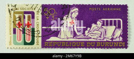 Timbre-poste annulé imprimé par le Burundi, qui montre l'infirmière de la Croix-Rouge avec le patient, 50th anniversaire de la Ligue des sociétés de la Croix-Rouge, vers 1969. Banque D'Images